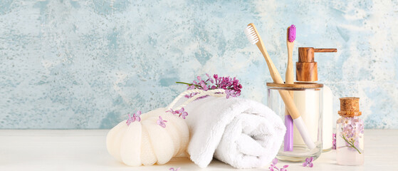 Bottles of liquid soap and serum, holder with bamboo tooth brushes, bast wisp and towel on grunge...