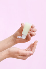 Woman applying sanitizer on pink background