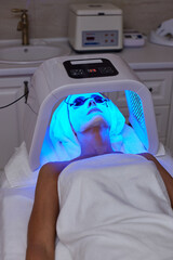 Woman getting facial treatment with led therapy.