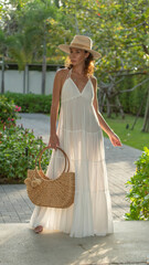 A beautiful young woman in a white dress and a straw hat with a wicker bag