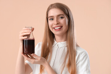Young woman with bottle of beet juice on beige background