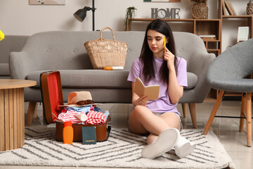 Young woman with suitcase making list at home