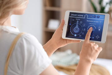 Young woman using smart home security system control panel in bedroom, closeup