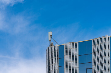 Fototapeta premium Broadcasting antenna on the roof of the administrative building against the background of a blue sky with light clouds...