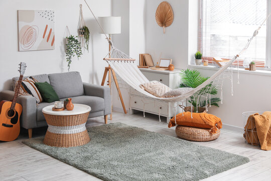 Interior of stylish living room with hammock, grey sofa and coffee table