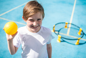 boy holding a yellow ball for a sport game spikeball. a child stands in front of a 