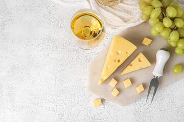 Board with tasty Swiss cheese and and glass of wine on light background