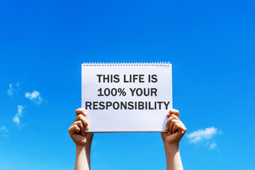 Hands holding a placard with inspirational quotes - This life is 100% your responsibility