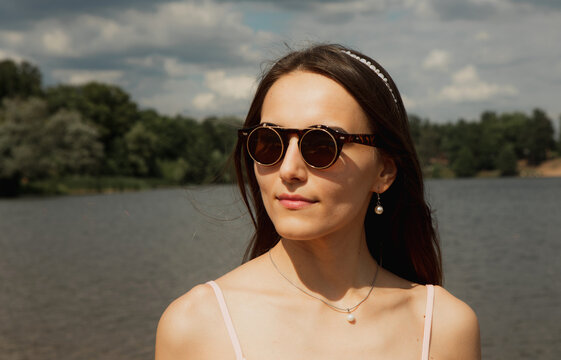 Beautiful fashionable woman outdoors. Young female model wearing sumglasses posing in summer park.