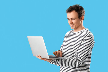 Young man with laptop on blue  background