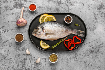 Tray of raw dorado fish with lemon and spices on light background