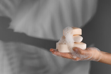 Hand with soap bars on grey background