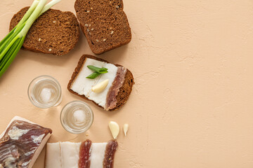 Shots with cold vodka and snacks on beige background
