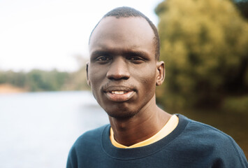 A young black man is walking in the park.