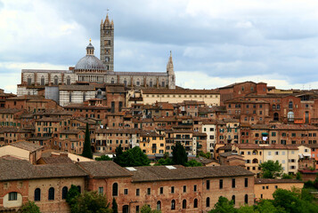 Fototapeta na wymiar View of the historic part of the city of Siena with the Duomo di Siena against a stormy sky in the Tuscany region of Italy