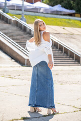 Portrait of a young beautiful blonde girl in long blue jeans skirt