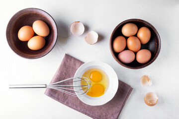 Top view brown chicken eggs in a bowl on the table with a whisk to beat the eggs.