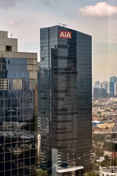 Building exterior of AIA with red white logo on top and reflection on glass windows.