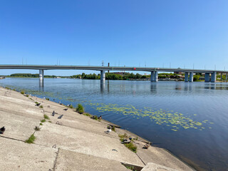 Fototapeta premium on a summer day, the reflection of the automobile bridge in the blue water of the river