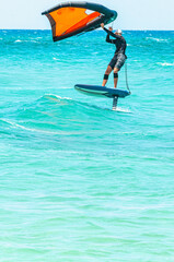 Front view, far distance of a young, male, in wet suit, wind surfing, on Atlantic ocean, off Florida coast