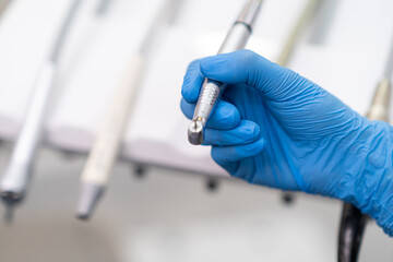 Stomatologist preparing drill of automatic dental machine to remove tooth decay in patient oral cavity in stomatology clinic doctor with equipment in medical cabinet