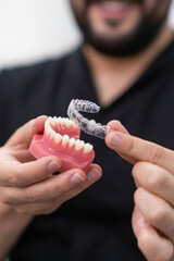 Doctor demonstrating clear aligners installation on artificial lower human jaw for orthodontic...