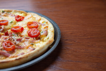 Small pizza in a dark pan on the table. Empty space.