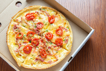 Small pizza in a cardboard box on the table. View from above.