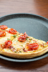 Pizza on a wooden table. Half a pizza in a dark frying pan.