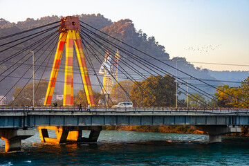 A statue of Shiva stands behind the Haridwar Bridge as the Ganga flows underneath. 