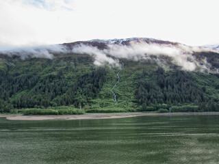 View of streams of water from melted ice running down a mountain into a lake in Juneau, Alaska.