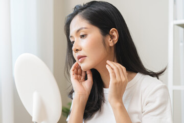 Anti aging beauty, happy asian young woman looking in mirror reflection at home, touching face skin satisfied with healthy moisturized, skin care treatment cosmetic for dry skin during morning routine