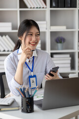 Beautiful Asian woman playing mobile phone in her break from work, she is a marketing manager of a startup company, female leader, supervisor, ceo. Female Leadership Concept.