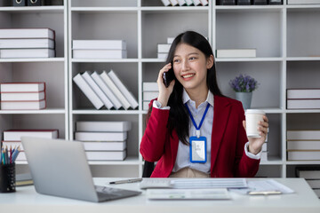 Asian woman talking on the phone, she is a salesperson in a startup company, she is calling customers to sell products and promotions. Concept of selling products through telephone channels.