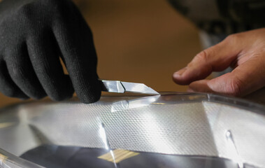 The process of installing a protective polyurethane film for paint on the front headlight of a car....