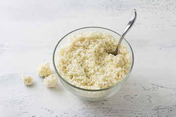 Shredded cauliflower, cauliflower rice or cauliflower couscous on a light blue table. Cooking delicious vegan healthy food