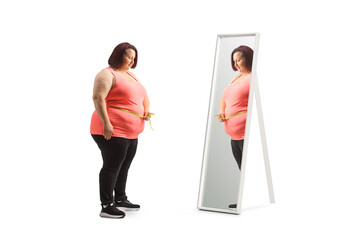 Overweight woman in front of a mirror measuring her waist