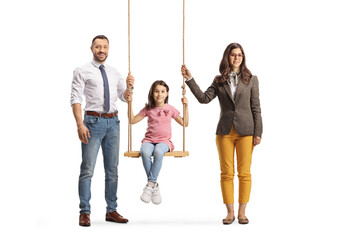 Fototapeta premium Mother and father standing next to their daughter on a swing