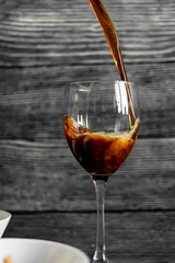 dark beer pours into a clear glass. dark background. dense beer foam. cooling drink