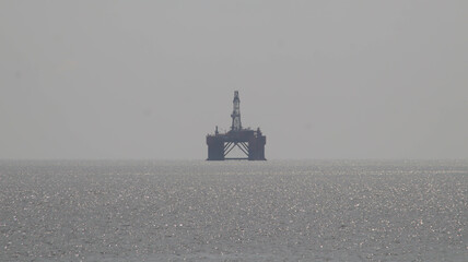 Offshore oil platform drilling site or oil rig project seen far in the middle of the sea.