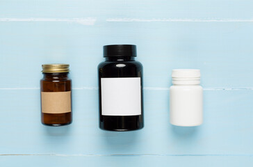 Plastic bottles with vitamins on wooden background, top view