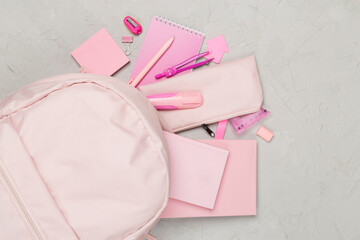 Pink school backpack with stationery on concrete background, top view