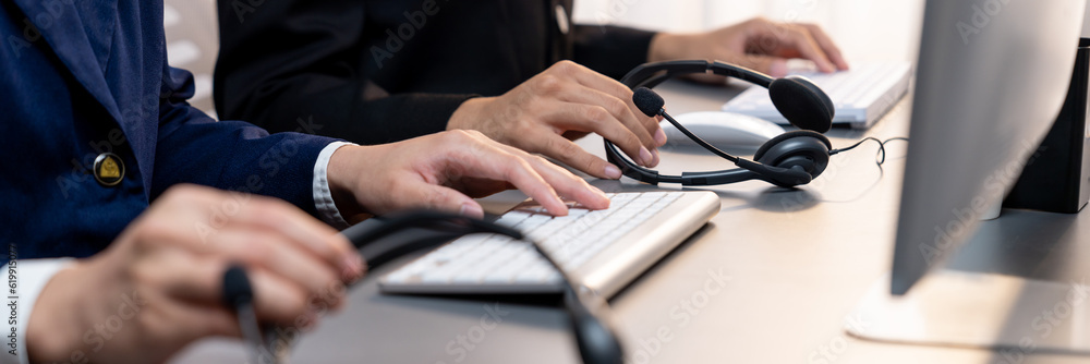 Aufkleber panorama focus hand holding headset on call center workspace desk with blur background of operator t