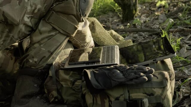 A soldier uses a portable charging station to charge a tablet and phone during a combat mission.