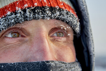 Portrait of a mature man in a knitted hat and a face mask close-up in the cold.