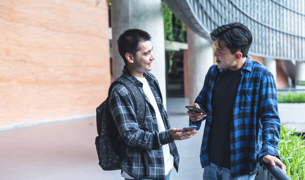 Two Asian male college students are using an application on their phones to scan a QR code. to increase communication channels. to education and technology concept.