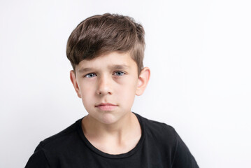 Portrait of a cute young boy of early school age on a light background, the boy is serious and a little tired, he wants to study less and play and walk more