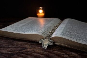 open bible with candle and silver cross