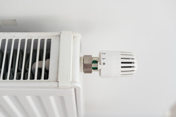 Building thermoregulation. The man turns the radiator knob.