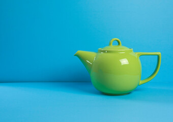 green ceramic teapot against a blue background